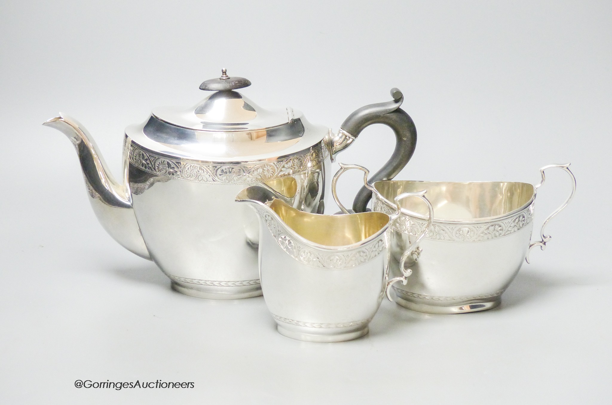 A George V three piece engraved oval silver tea set, C.S. Green & Co, Birmingham, 1924, gross 26oz.